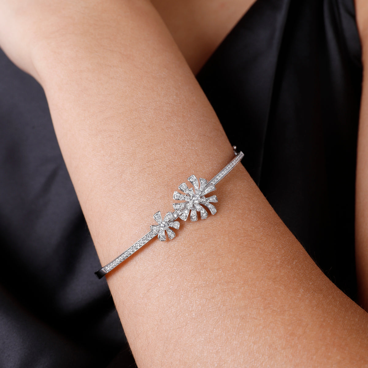 Feminine bangle features a centerpiece flower design of diamond stone studded petals.