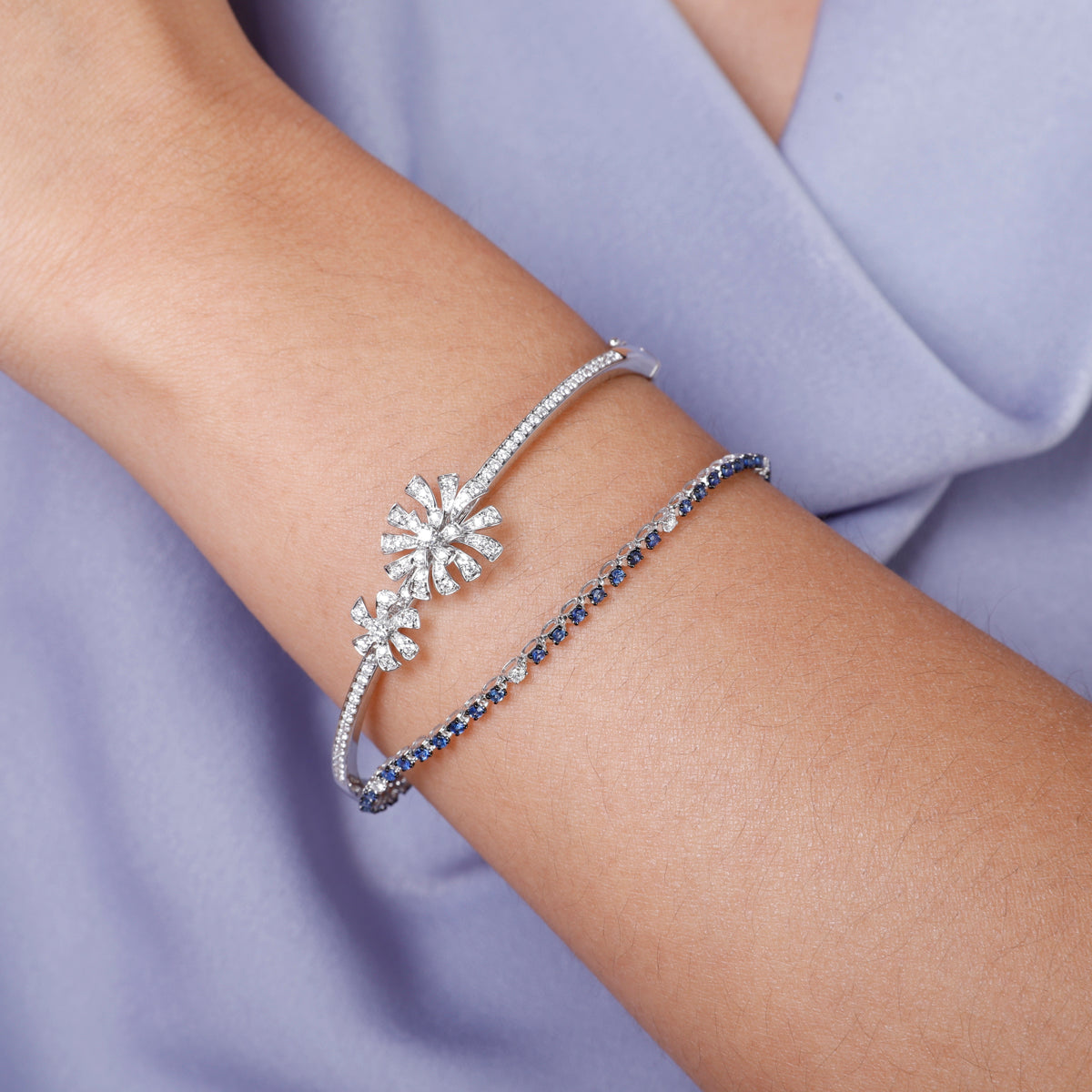 Feminine bangle features a centerpiece flower design of diamond stone studded petals.