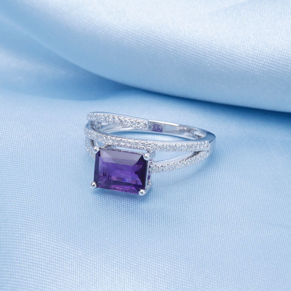 Luxurious ring showcases a semi-precious stone enveloped by three dazzling diamond bands