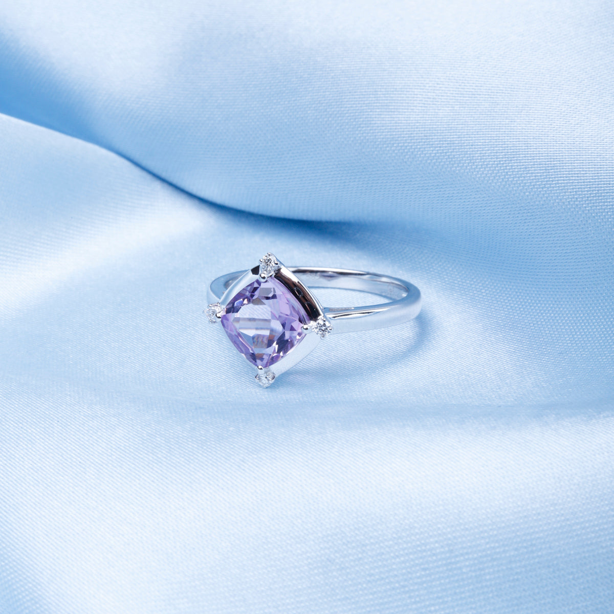 Stunning ring with a gemstone at an angle with diamonds at each corner to accentuate its color. 
